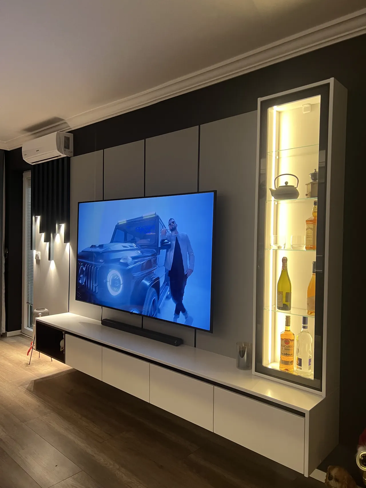 TV-Wand mit schwebendem Lowboard und beleuchteter Glasvitrine
